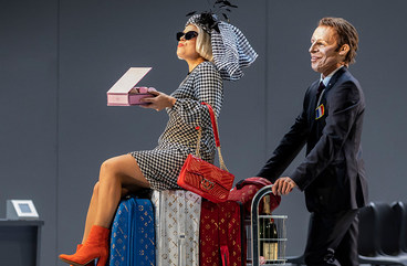 Szene aus "Il viaggo a Reims": Sängerin sitz auf Koffern auf einem Gepäckwagen, der von einem Sänger geschoben wird