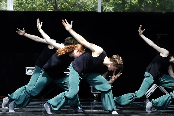 Tänzerinnen und Tänzer in schwarzen Oberteilen und türkisfarbenen Hosen in moderner Tanzpose auf der Palucca Sommerbühne