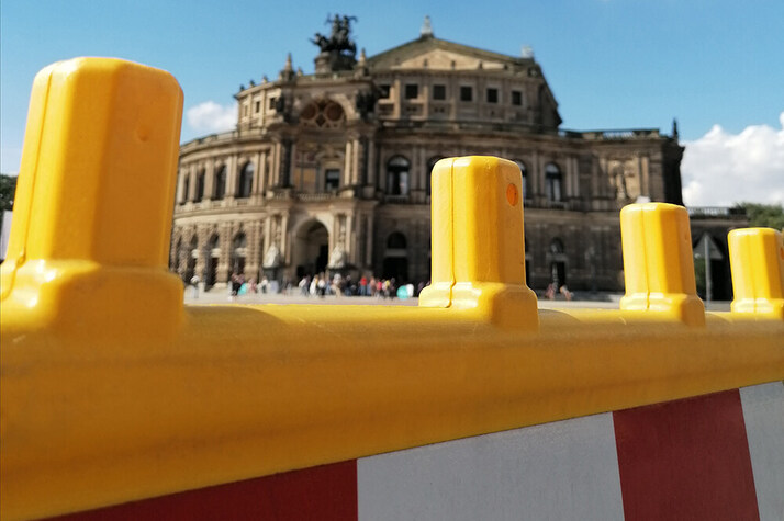 Gelber Absperr-Zaun mit weiß-roten Streifen am Theaterplatz, im Hintergrund die Semperoper