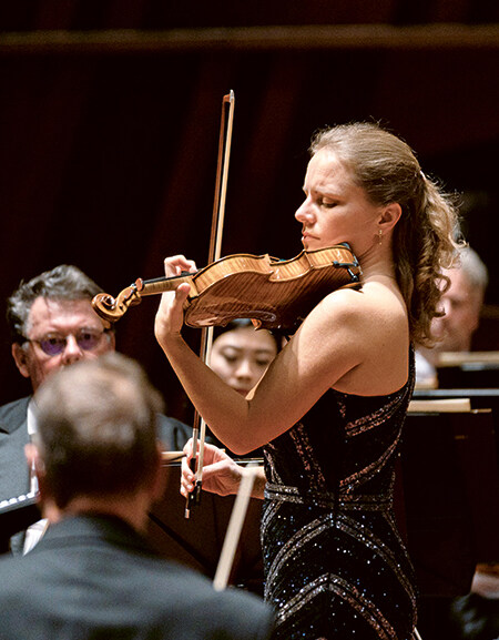 Julia Fischer mit Violine inmitten von Orchestermusikern