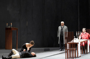 Szene aus "Tosca": Sängerin kniet neben liegendem Sänger und hält seine Hand, im Hintergund befinden sich 4 weitere Sänger 