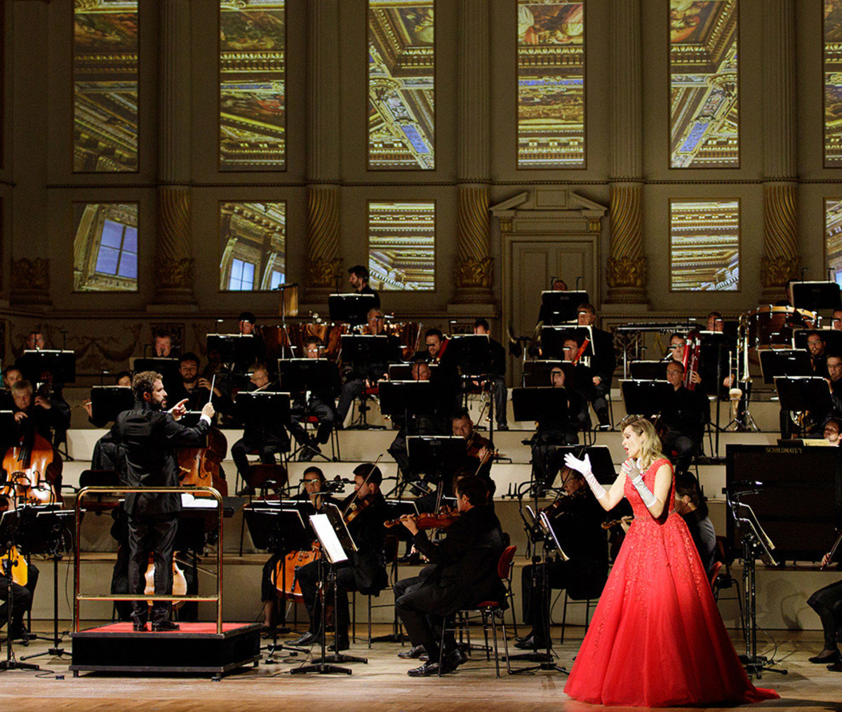 Eine Sängerin im roten Kleid steht vor dem Orchester