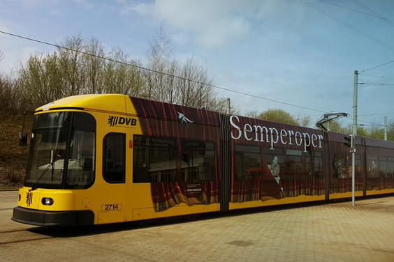 Gelbe Straßenbahn mit rotem Vorhang und Schriftzug »Semperoper« als Werbeaufdruck
