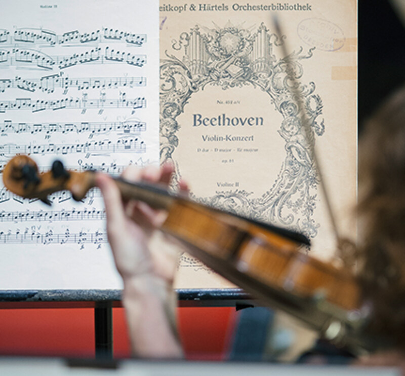 Detailaufnahme einer Violinistin mit Beethoven-Noten © Semperoper Dresden/Oliver Killig Blick über die Schulter einer Violinistin mit Notenmaterial von Beethoven auf dem Pult