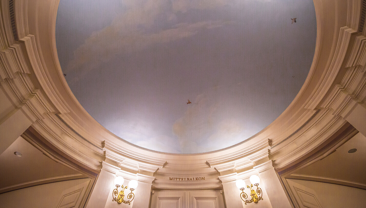 Mit blassblauem Himmel, weißen Wolken und kleinen Vögeln bemalte Decke vor dem Mittelbalkon im Foyer der Semperoper