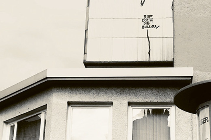 Die Fotoaufnahme der Künstlerin Rosemarie Trockel zeigt ein Haus mit drei eingeschlagenen Scheiben, darüber der gesprayte Schriftzug »Ruf doch die Bullen«.