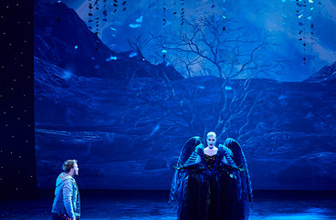Szene aus "Die Zauberflöte": Sängerin steht mittig auf der Bühne, ein Sänger kniet links neben ihr