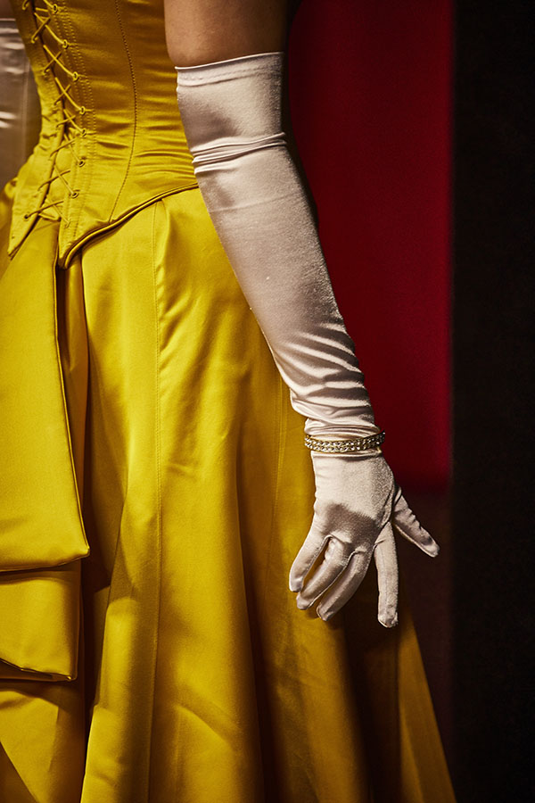 Kostümdetail »La traviata«: ein weißer, glänzender Handschuh reicht bis über den Ellenbogen, am Handgelenk ein schmaler, mit Steinen besetzter Goldreif